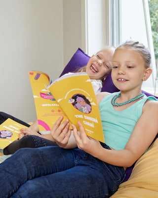 Two little girls reading the Emberá Chamí Wipala Adventure